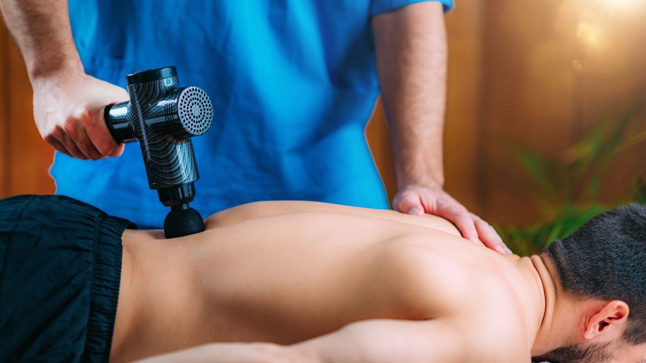 https://sciatica.clinic/wp-content/uploads/2021/04/massage-gun-treatment-physical-therapist-massaging-EESEKKK_02.jpg